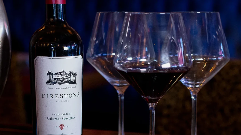 Bottle of Firestone Cabernet Sauvignon and three glasses, one poured.
