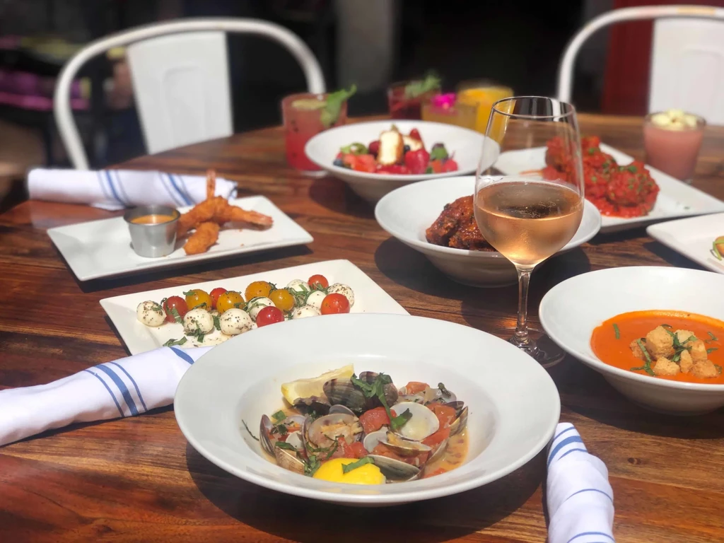 Rustic table with diverse food spread: seafood, soup, salad, and drinks.