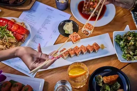 Overhead view of an Asian dining table with sushi, lobster, and chopsticks.