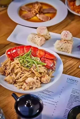 Restaurant table with lobster pasta, dumplings, and other appetizers.