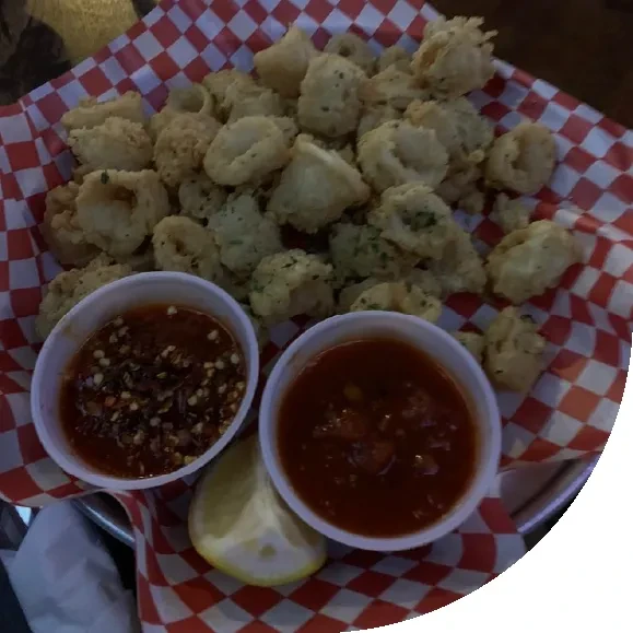 Basket of fried calamari, two sauces, and a lemon wedge.