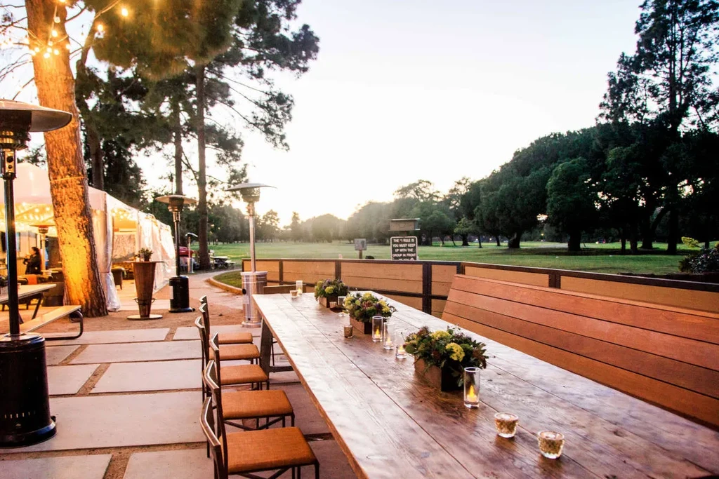 Evening outdoor dining with lit table, patio heaters, and golf course.