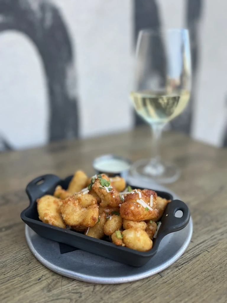 Fried appetizers with cheese, herbs, and white dipping sauce.