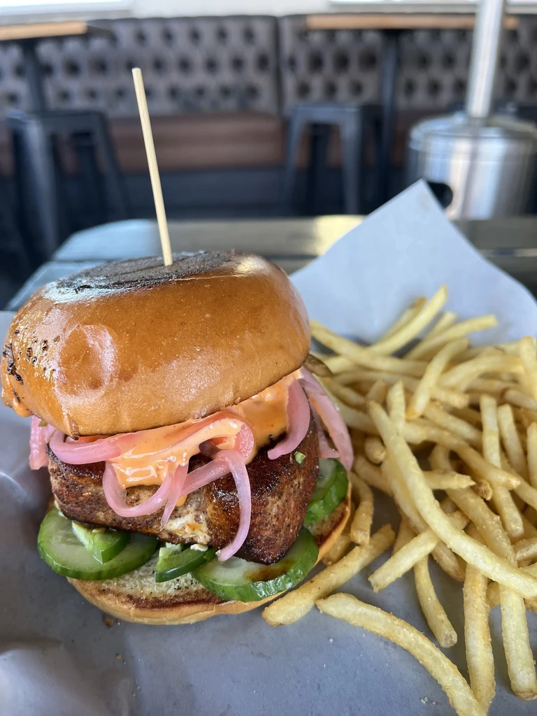 Gourmet burger with toppings and crispy fries on a tray.