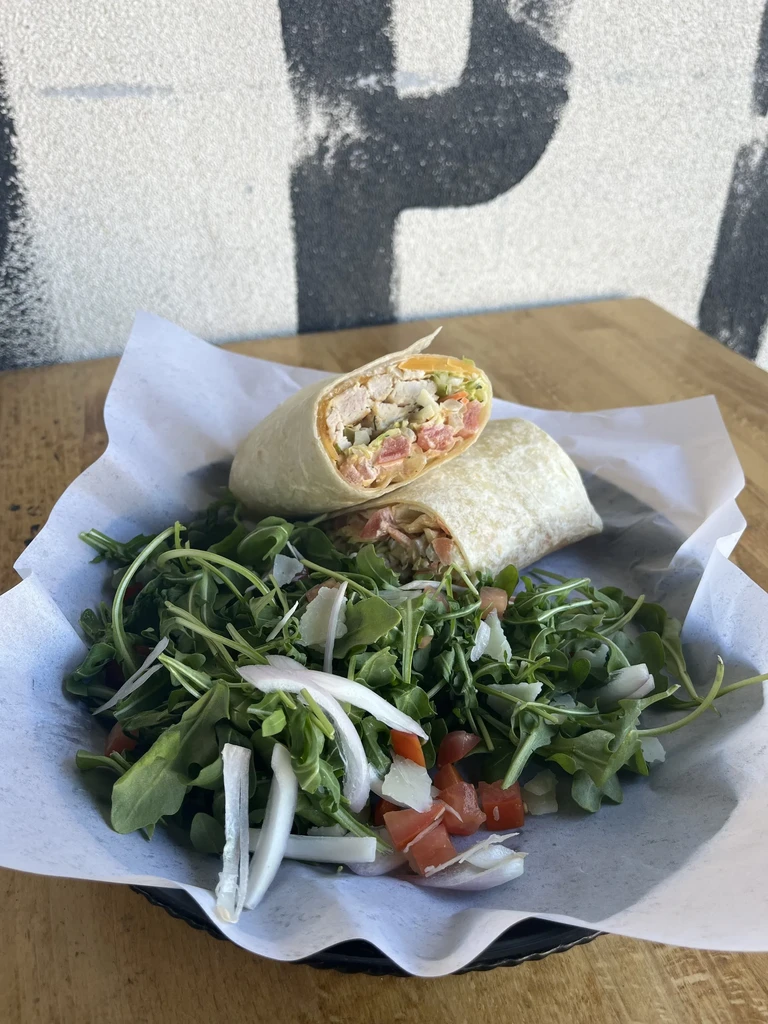Chicken and veggie wrap halves served with a side arugula salad.