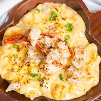 Close-up of creamy shrimp macaroni and cheese in a heart-shaped wooden bowl.