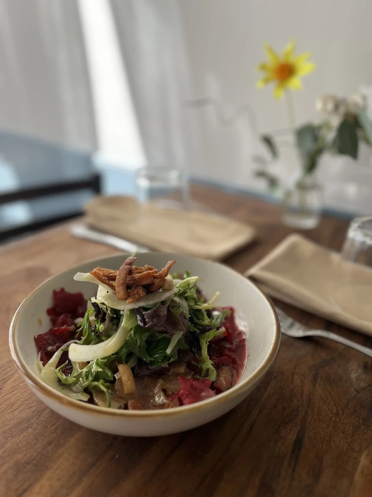 Colorful layered salad bowl on a rustic wooden table.