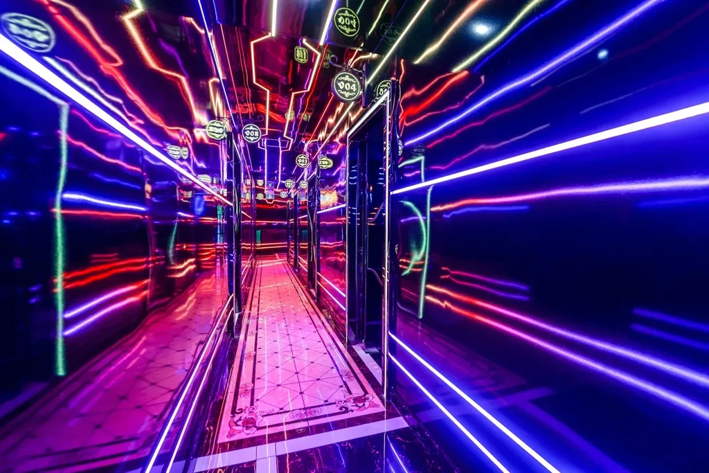 Reflective hallway with blue, purple, and red neon lights, numbered signs.