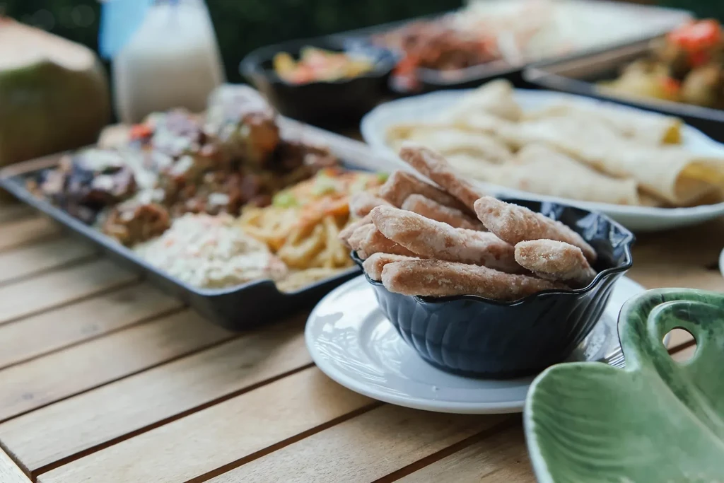 Close-up of pastries, meat, coleslaw, and other dishes on an outdoor table.