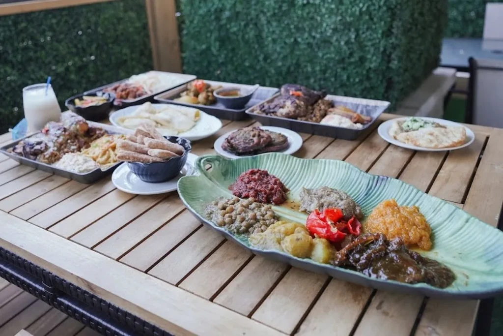 Vibrant Ethiopian-style food spread and a drink on a wooden table.