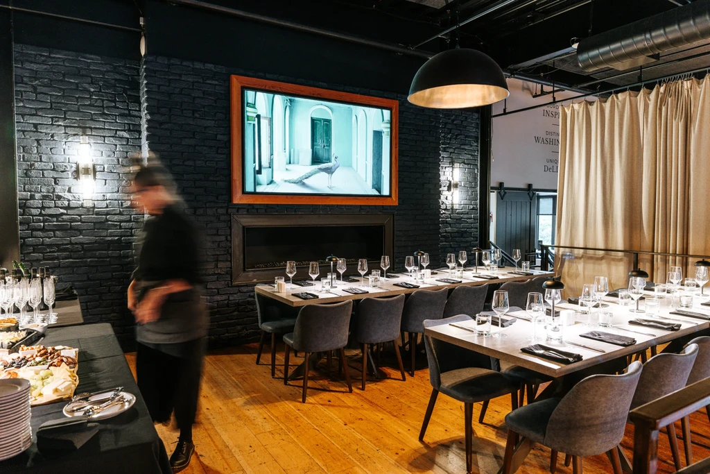 Modern restaurant interior with set dining tables, buffet, and brick wall.