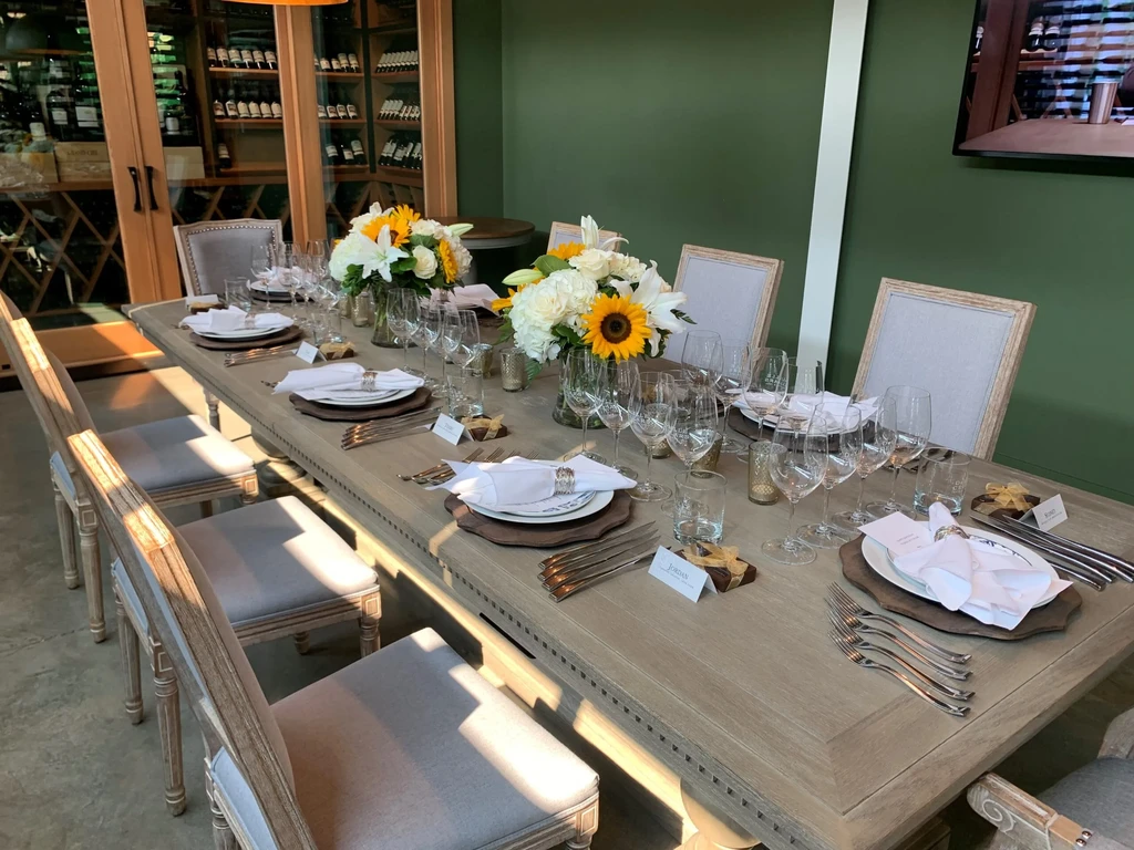 Elegant dining table set with flowers, name cards, and wine cabinet.