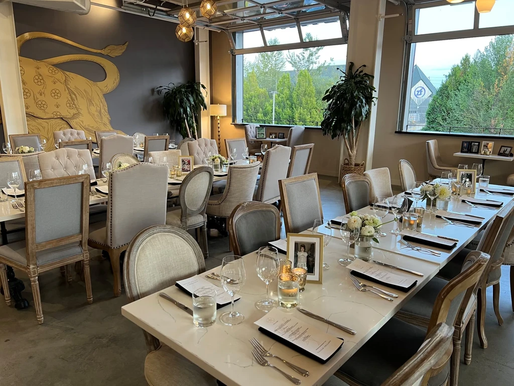 Elegant dining room with long tables, floral centerpieces, and a gold animal mural.