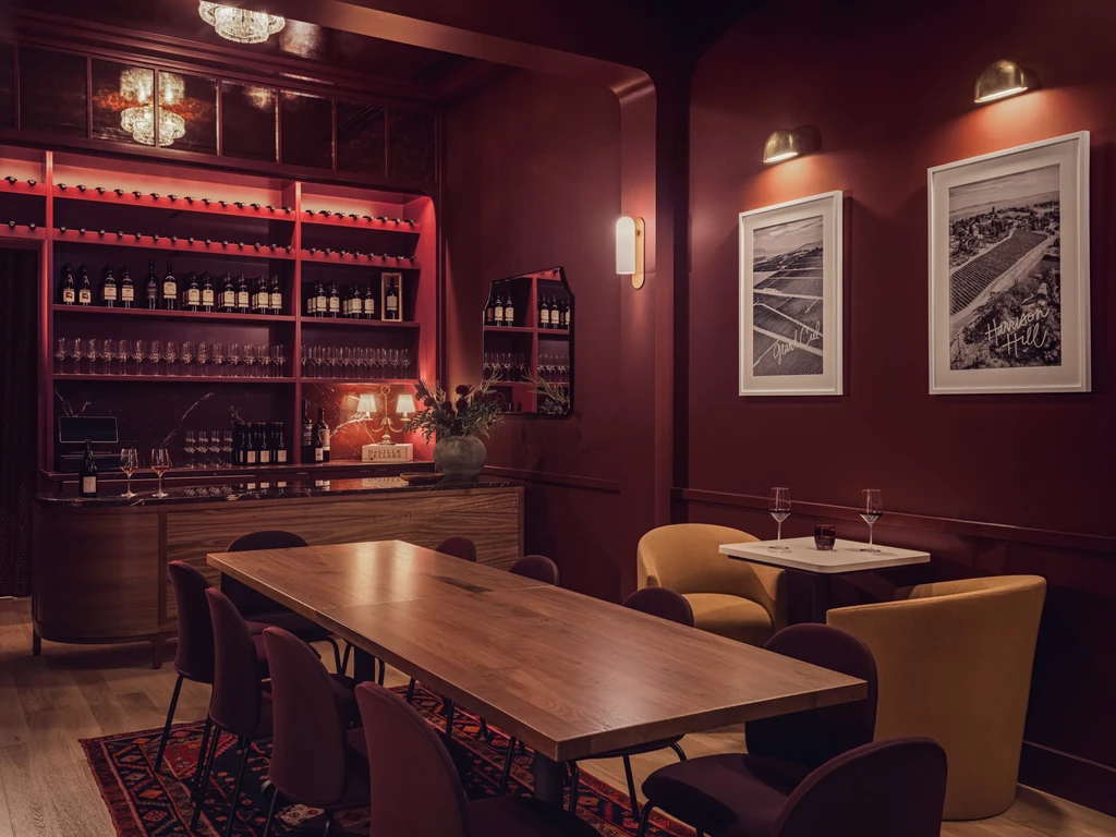 Red private dining room with wine display, long table, and armchairs.
