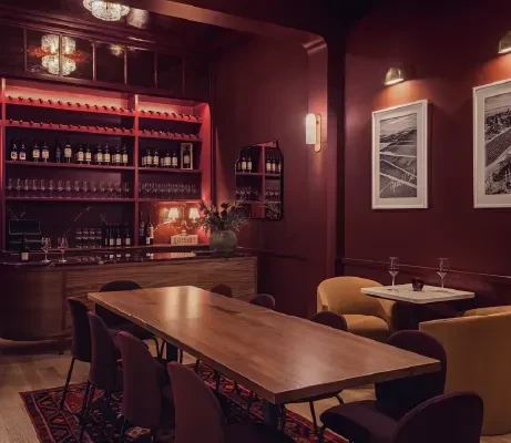 Burgundy wine bar interior with diverse seating and well-stocked wine display.