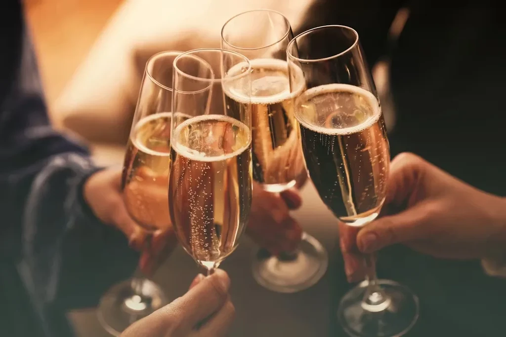 Hands clinking five sparkling champagne flutes together in a toast.