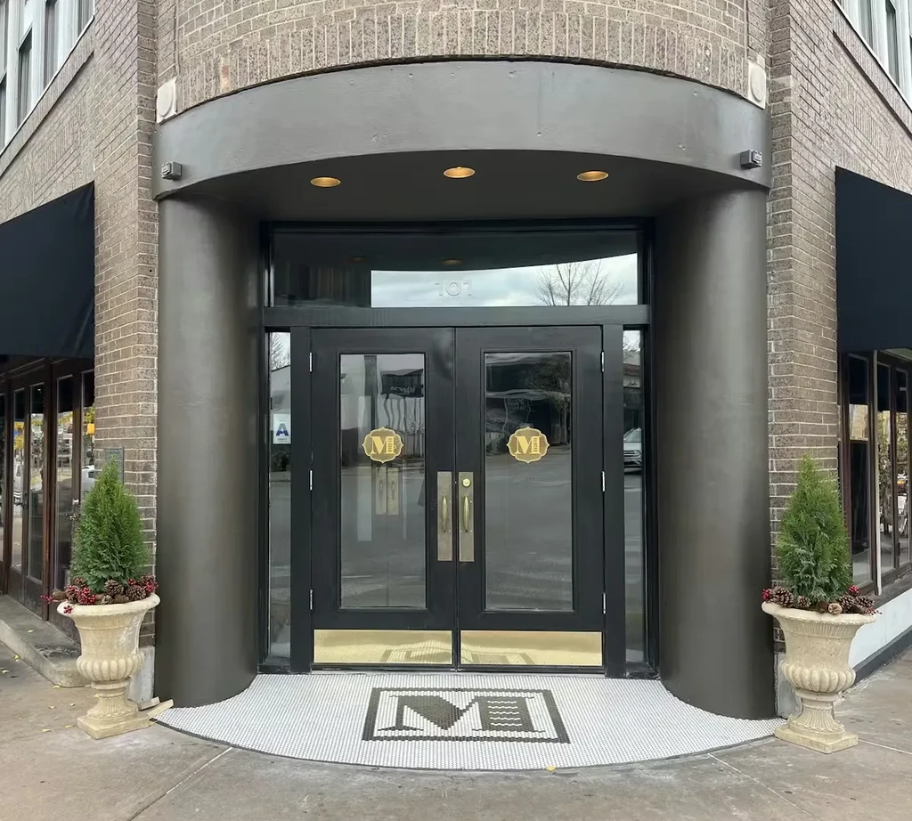 Restaurant exterior with dark double doors, '101' above, and mosaic 'M'.