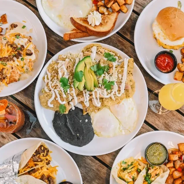 Overhead view of a wooden table with various breakfast and brunch plates.