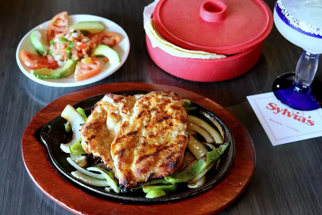 Sizzling chicken fajitas with onions, peppers, avocado, and margarita.