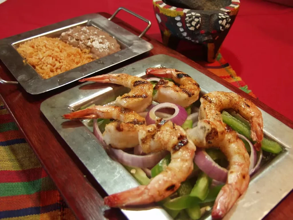 Grilled shrimp with bell peppers, rice, beans, and molcajete.
