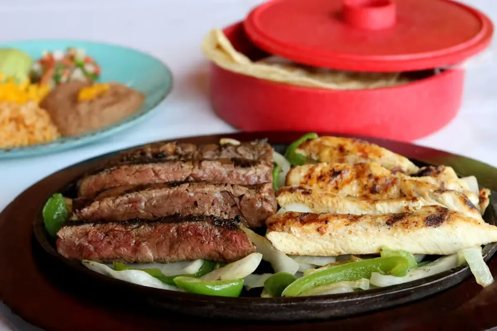 Sizzling cast iron skillet with steak and chicken fajitas.