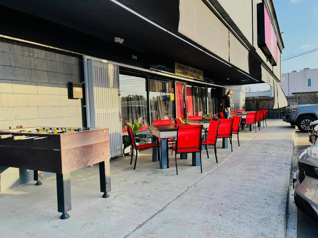 Outdoor patio with red chairs, foosball table, and parked cars.
