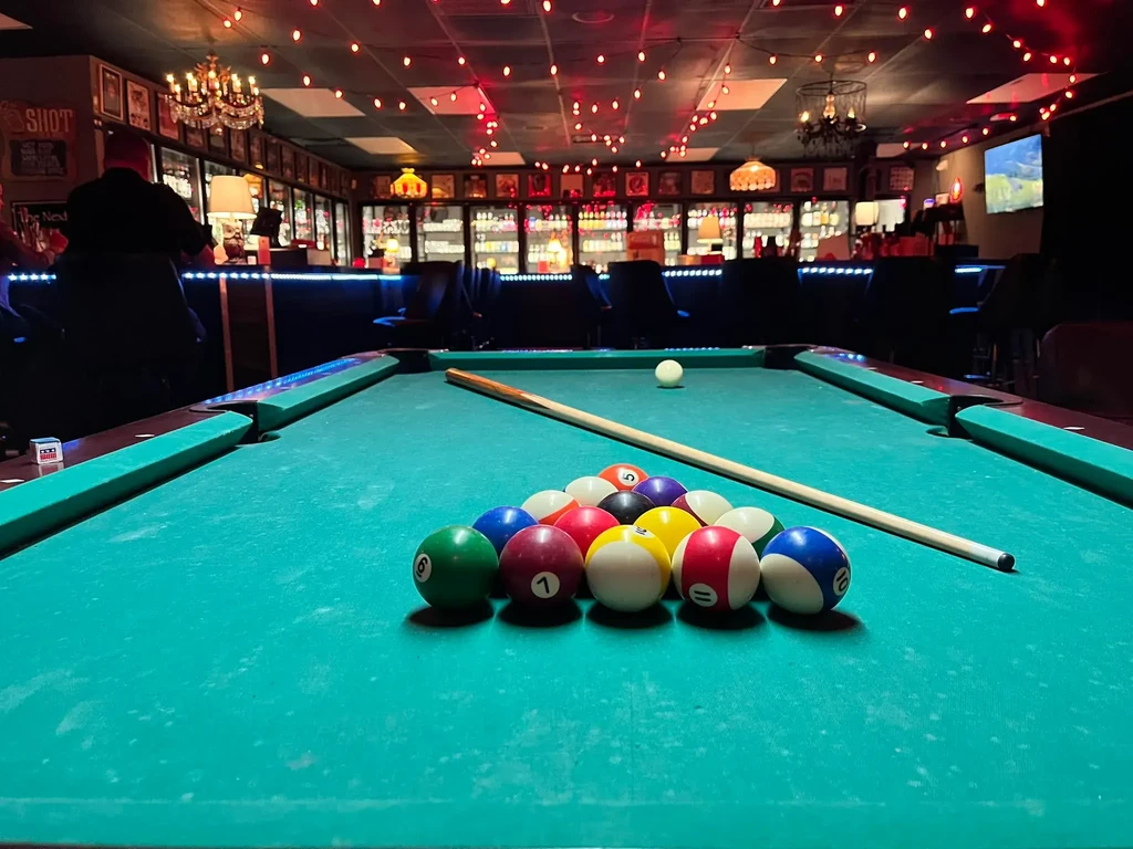 Pool table in a dimly lit bar with blue neon lighting.