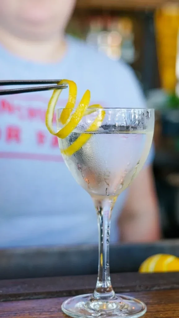 Coupe glass with a clear drink and a spiraled lemon peel.