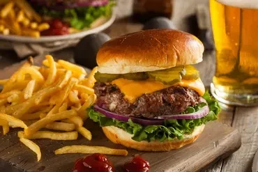 Cheeseburger and french fries on a wooden cutting board.
