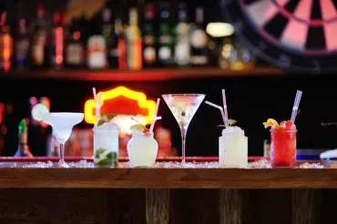Colorful cocktails lined up on a bar counter with garnishes.