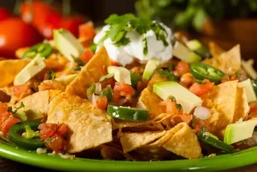 Nachos with meat, beans, jalapeños, avocado, and sour cream.