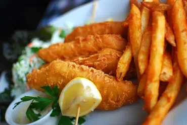 Close-up of a plate of golden-brown fish and chips with lemon.