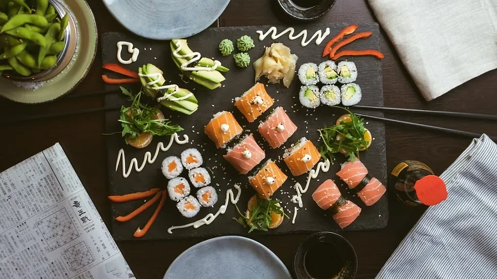 Overhead shot of a sushi platter with various rolls, edamame, and chopsticks.