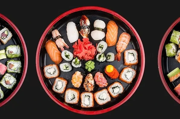 Three round platters filled with various types of sushi and rolls.