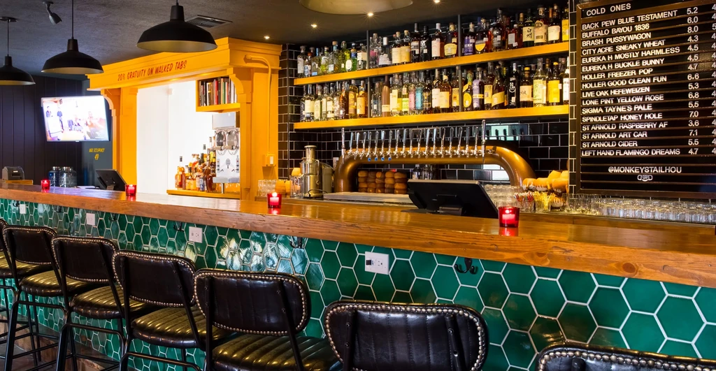 Modern bar interior with hexagonal tiles, liquor bottles, and beer taps.