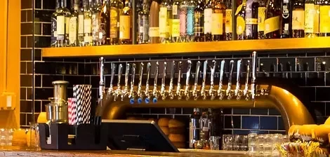 Polished brass beer tap system with multiple spouts and liquor bottles.