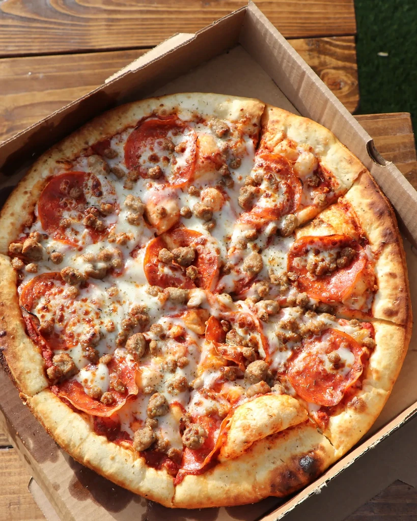 Pepperoni and sausage pizza in a cardboard delivery box.