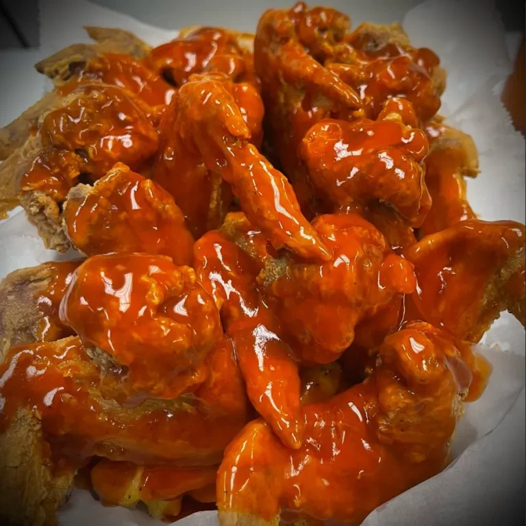 Fried chicken wings coated in a bright orange, glossy sauce.