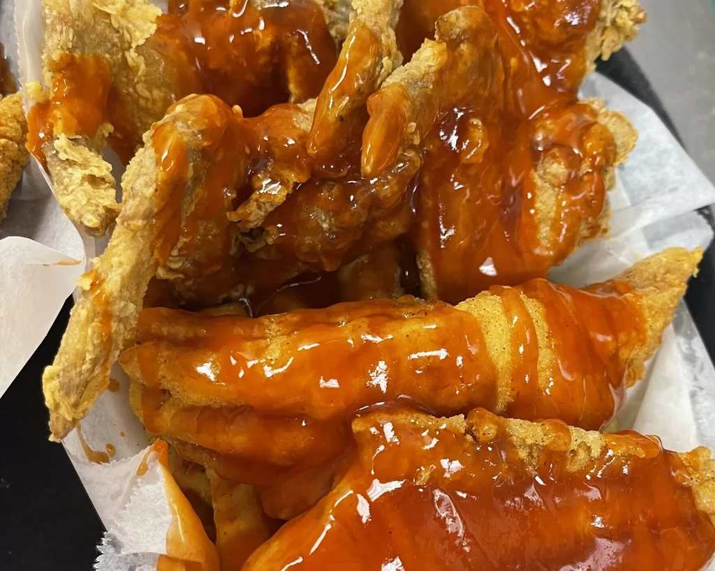 Several crispy fried chicken wings coated in orange-red sauce.