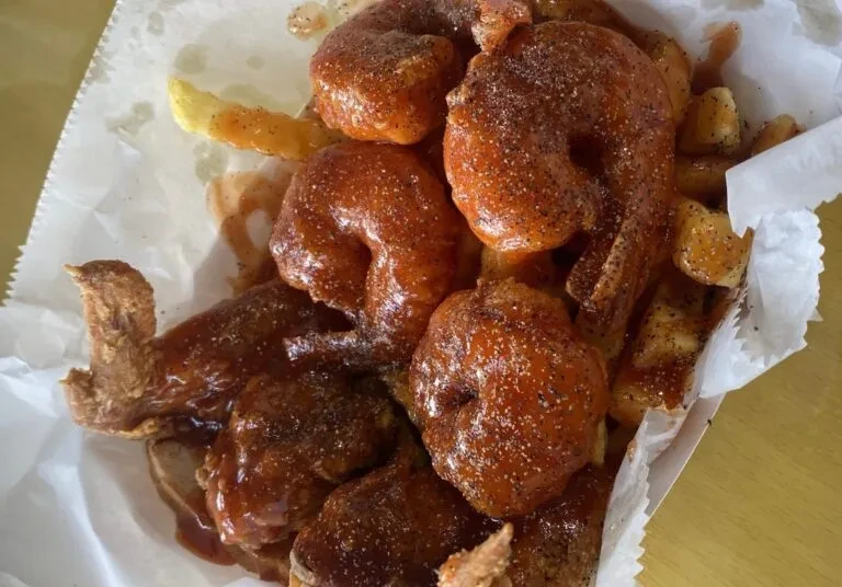 High-angle close-up of fried shrimp and french fries in a white tray.