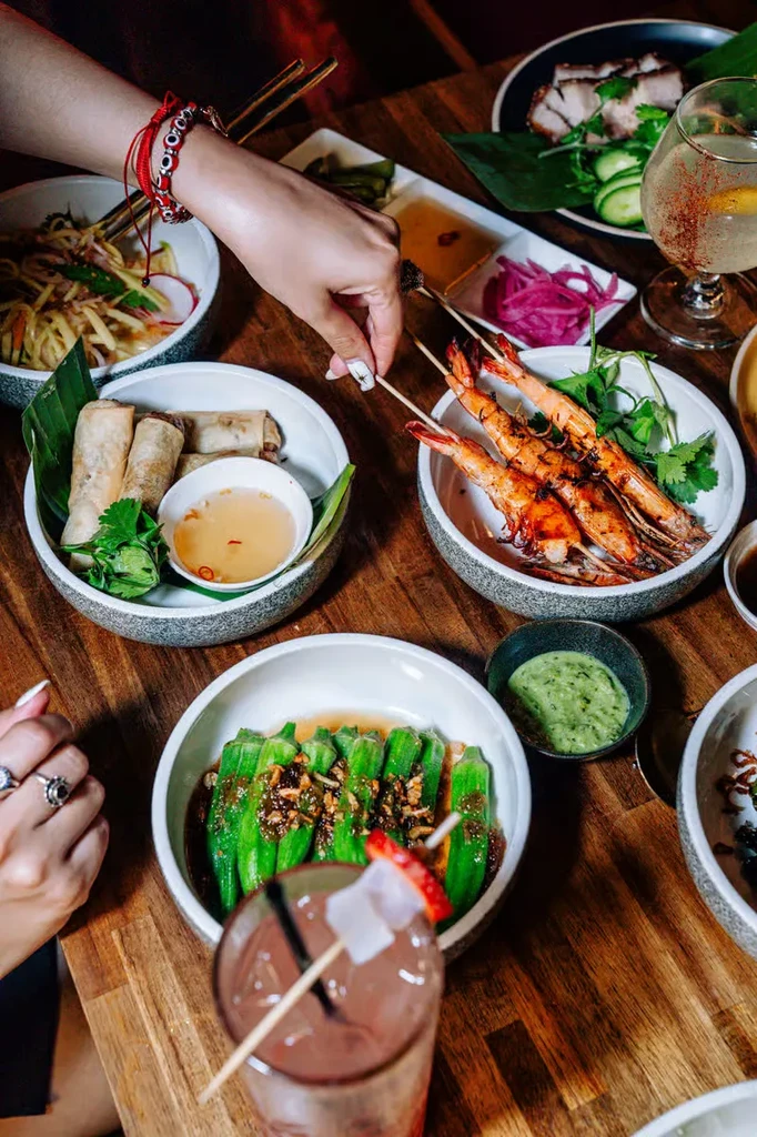 Overhead view of a restaurant table with dishes, drinks, and hands.
