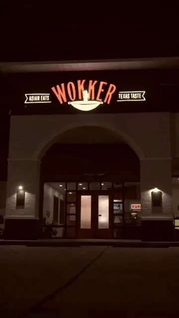 Exterior of a restaurant named "WOKKER" lit at night.