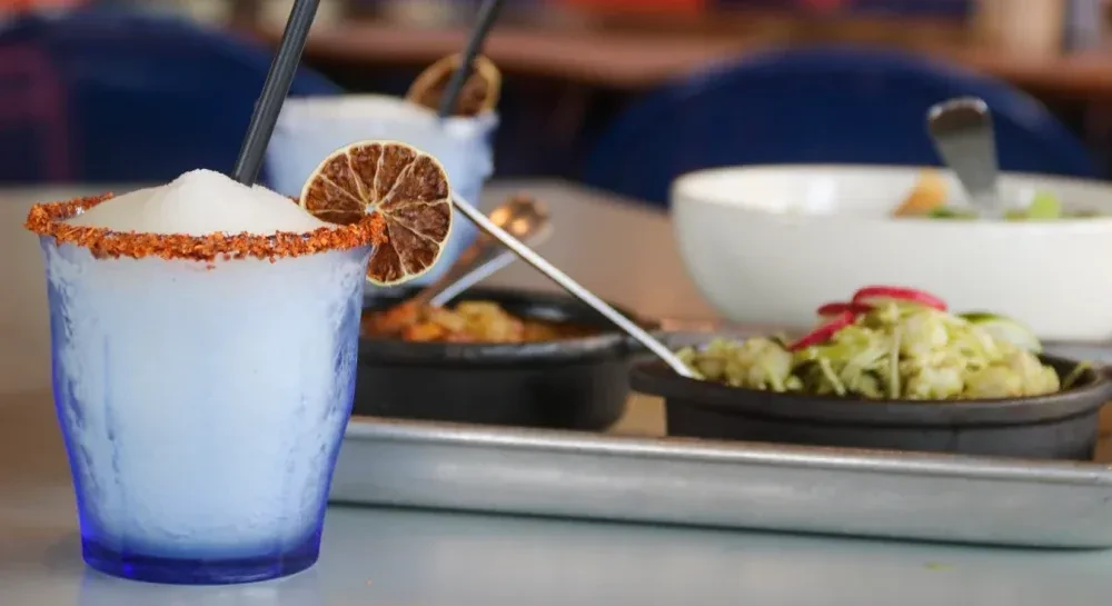 Frosty blue drink with chili-lime rim, dried lime, and dark straw.