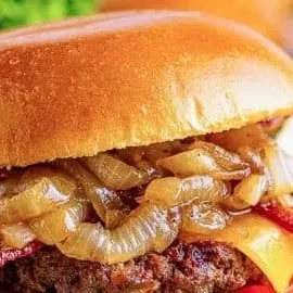 Close-up of a gourmet burger with caramelized onions and cheddar cheese.