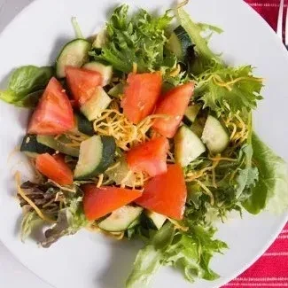 Fresh salad with lettuce, tomatoes, cucumbers, and shredded cheese.