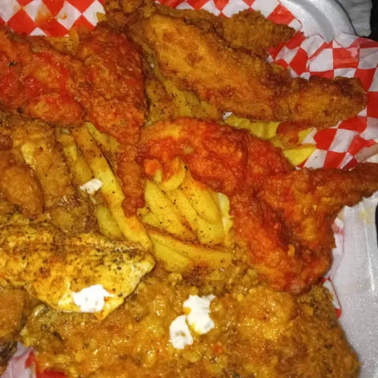 Fried chicken wings and french fries in a takeout container.