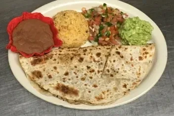 Overhead shot of a quesadilla meal with beans, rice, salsa, guacamole.