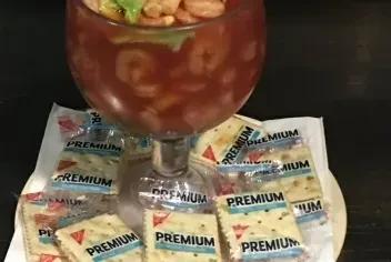 Shrimp cocktail in a goblet glass, with saltine crackers.