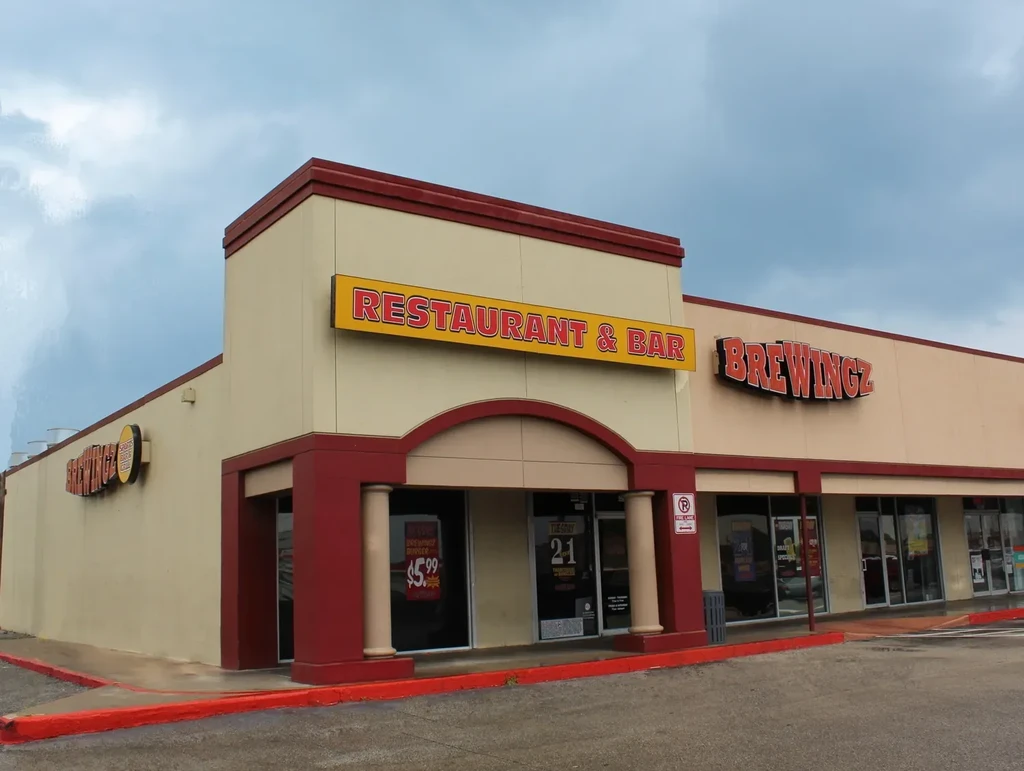 Exterior of a tan commercial building housing BREWINGZ restaurant and bar.