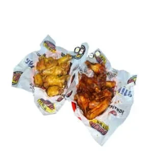 Two servings of chicken in white paper wrappers against a white background.